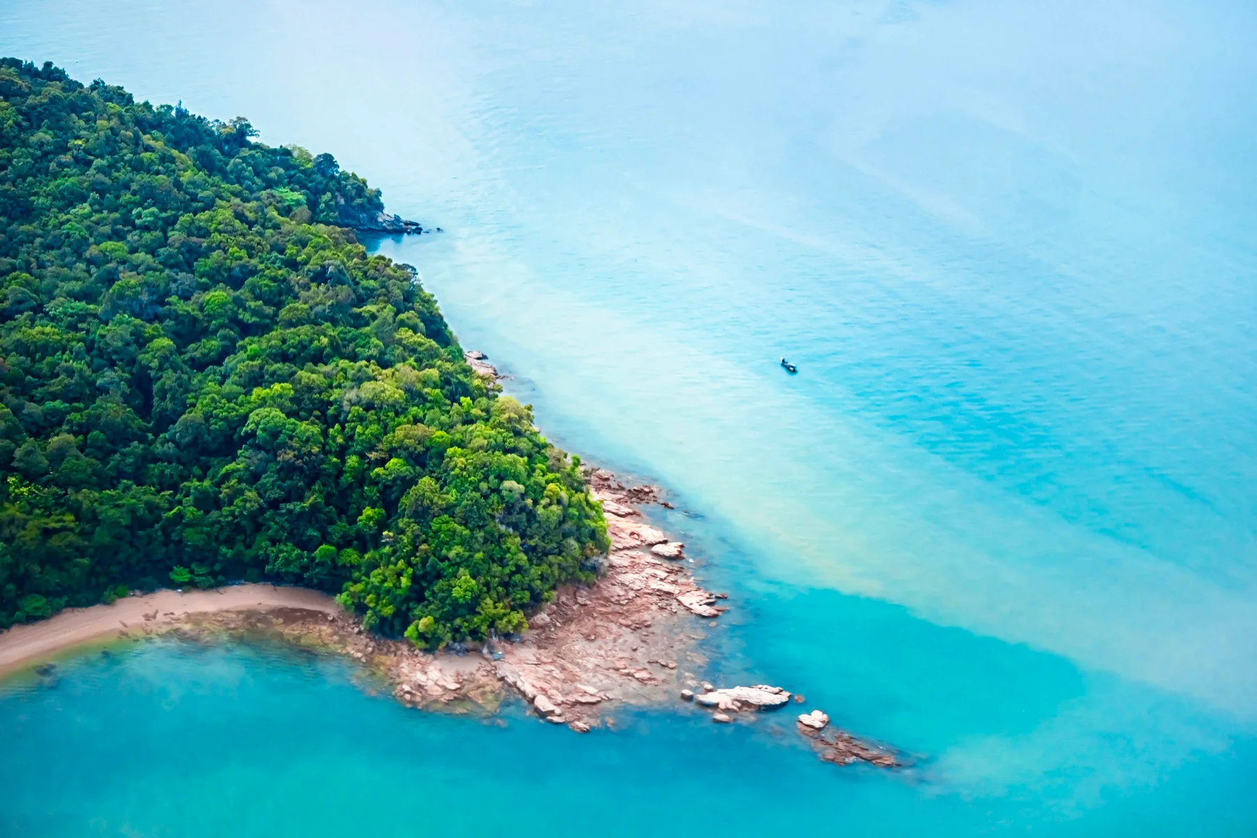 A green Langkawi headland meeting clear turquoise water